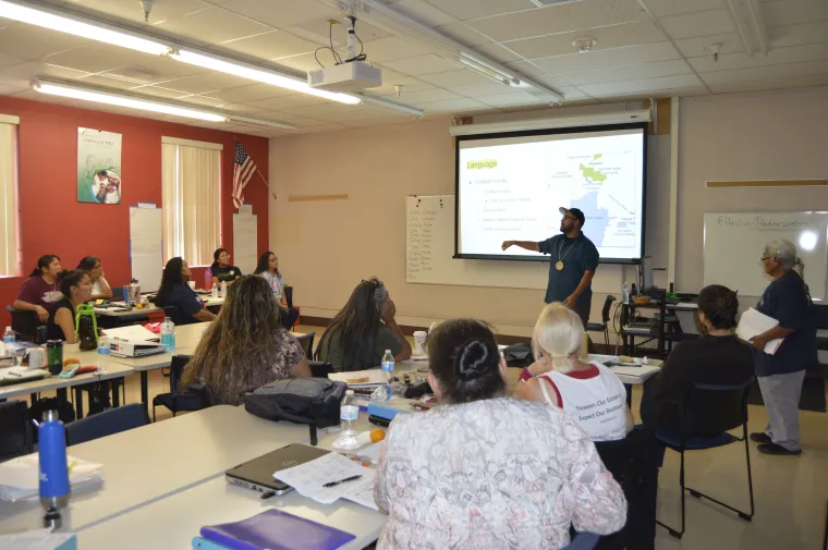 a male presenting in front of the class using screen