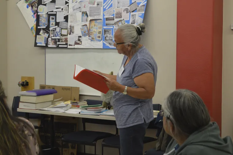 a female looking into a red book in front of the class